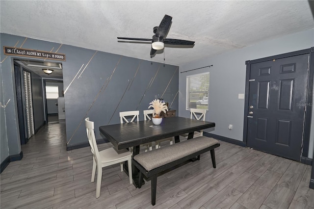 dining room with a ceiling fan, wood tiled floor, a textured ceiling, and baseboards