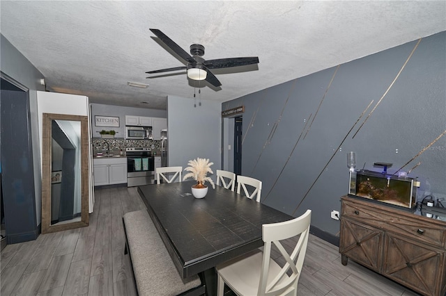 dining area featuring a textured ceiling, ceiling fan, and light wood-type flooring