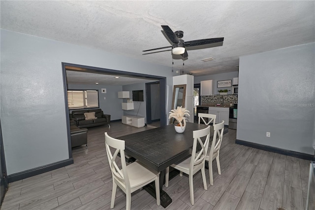 dining area featuring a ceiling fan, wood tiled floor, a textured ceiling, and baseboards