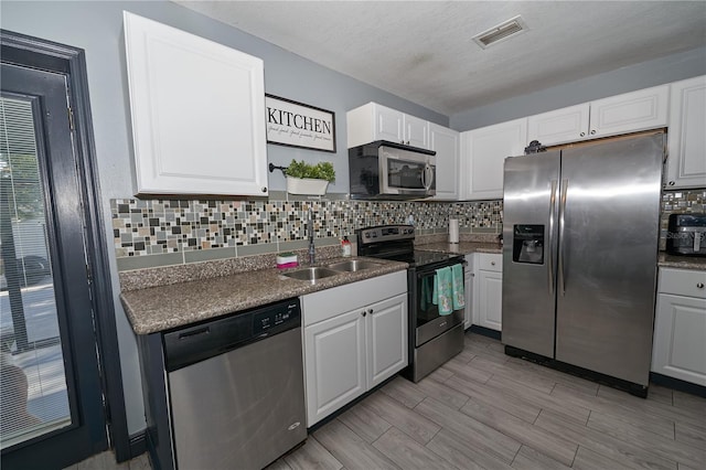 kitchen with tasteful backsplash, visible vents, white cabinets, stainless steel appliances, and a sink