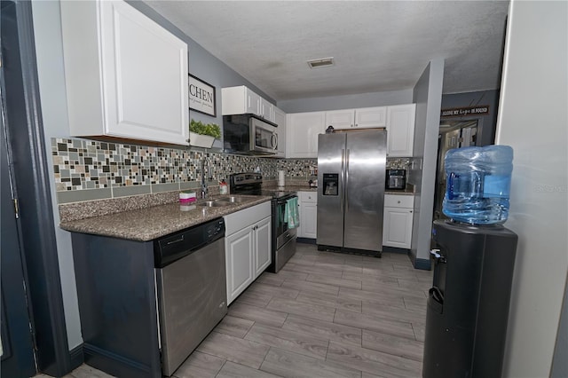 kitchen with tasteful backsplash, visible vents, appliances with stainless steel finishes, white cabinetry, and a sink