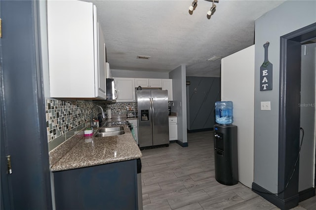 kitchen with stainless steel appliances, visible vents, backsplash, white cabinetry, and a sink