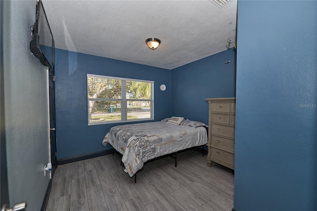 bedroom with baseboards and wood finished floors