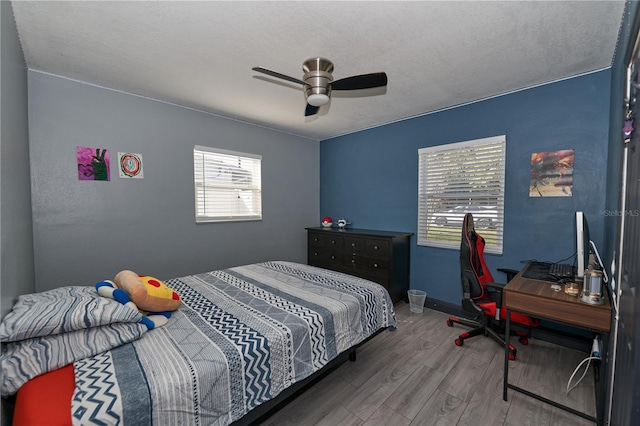 bedroom with baseboards, a textured ceiling, a ceiling fan, and wood finished floors