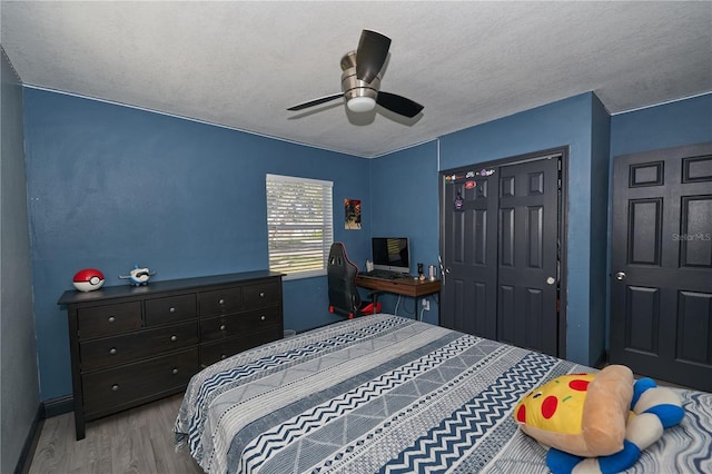 bedroom with a textured ceiling, a closet, wood finished floors, and a ceiling fan