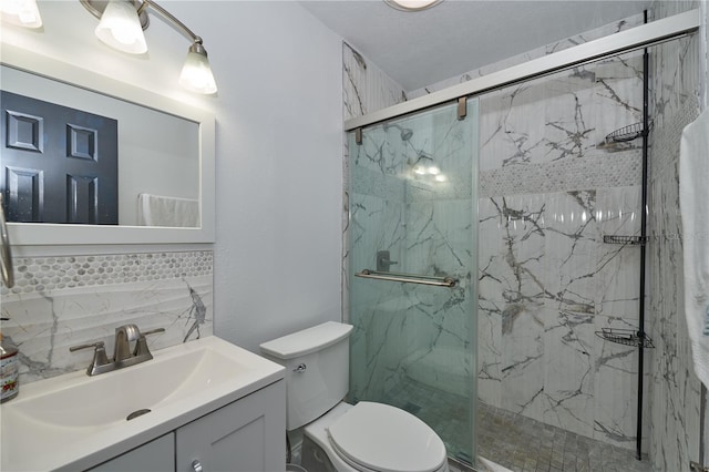 bathroom with a marble finish shower, toilet, vanity, and decorative backsplash