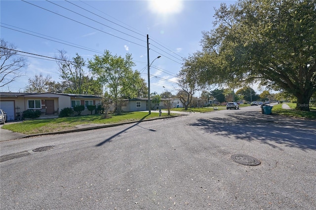 view of street featuring curbs, street lighting, sidewalks, and a residential view