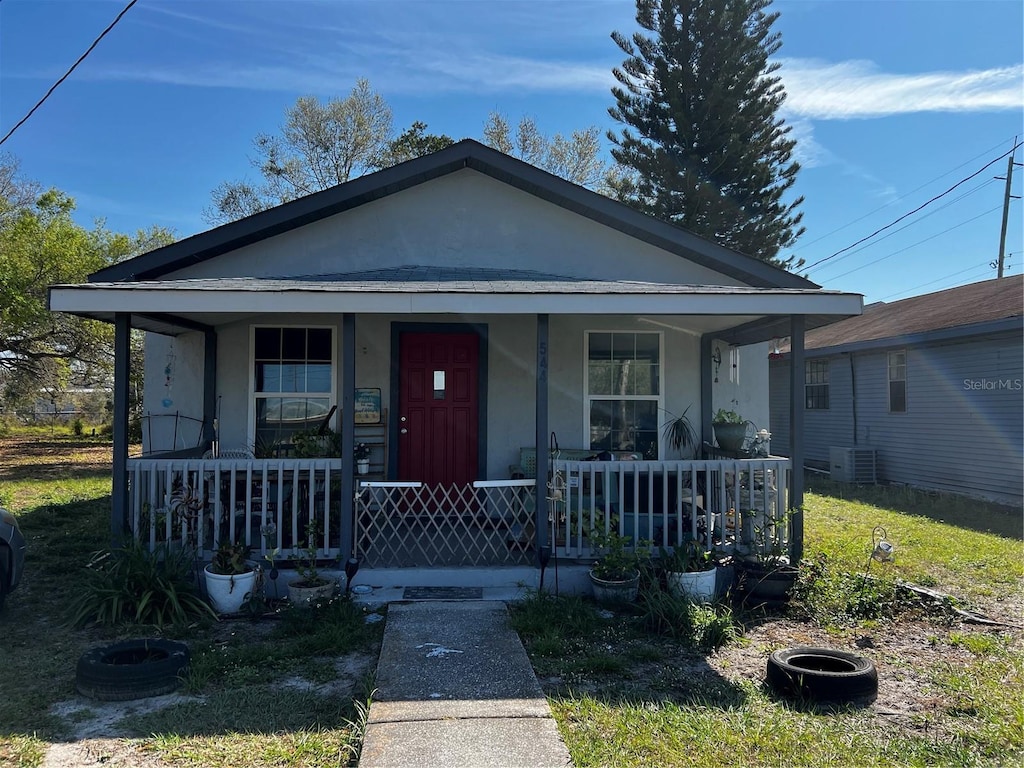 view of front facade featuring central AC unit, a porch, and stucco siding