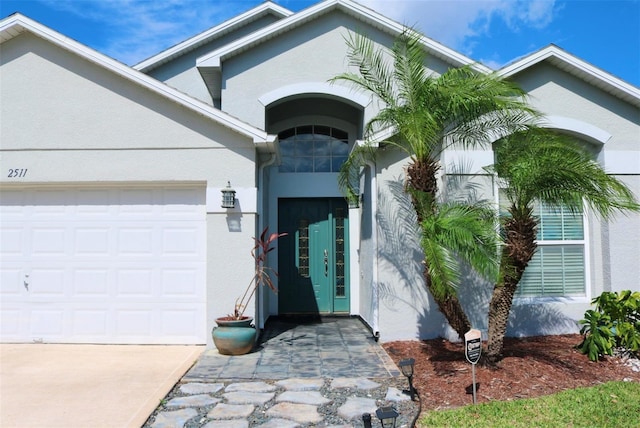 entrance to property featuring an attached garage and stucco siding