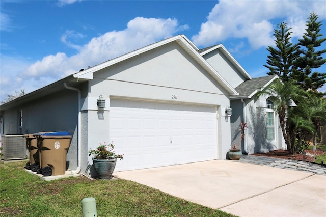 view of side of property featuring an attached garage, central air condition unit, concrete driveway, and stucco siding