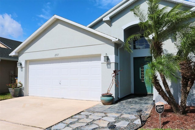 view of front of property featuring driveway, an attached garage, and stucco siding