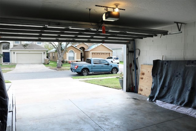 garage featuring concrete block wall, a residential view, and a garage door opener