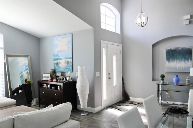 entrance foyer with a towering ceiling, baseboards, and wood finished floors