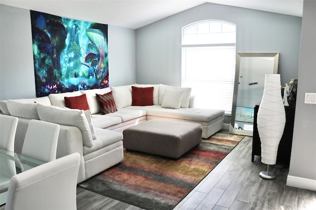 living area featuring vaulted ceiling, baseboards, and wood finished floors