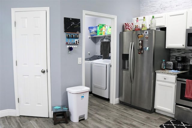 kitchen featuring white cabinets, light wood-style flooring, stainless steel appliances, and separate washer and dryer