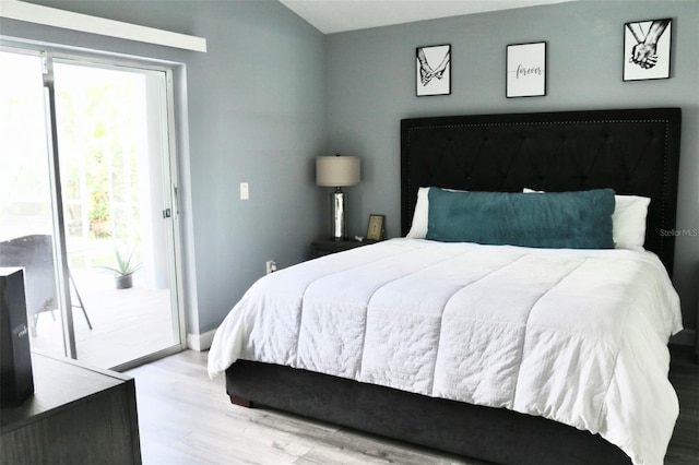 bedroom featuring lofted ceiling, access to outside, and wood finished floors