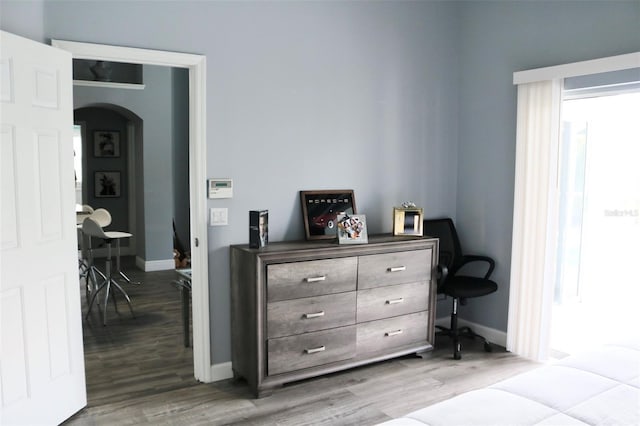 bedroom featuring arched walkways, baseboards, and wood finished floors