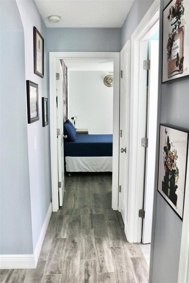 corridor with wood finished floors and baseboards