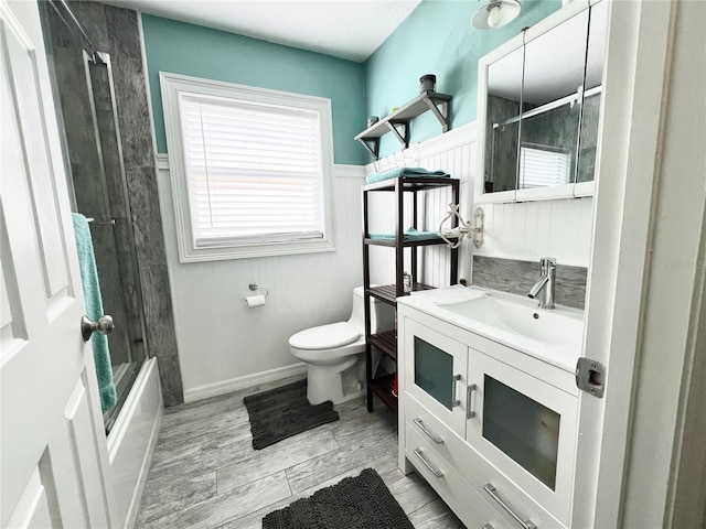 bathroom with wainscoting, plenty of natural light, vanity, and toilet