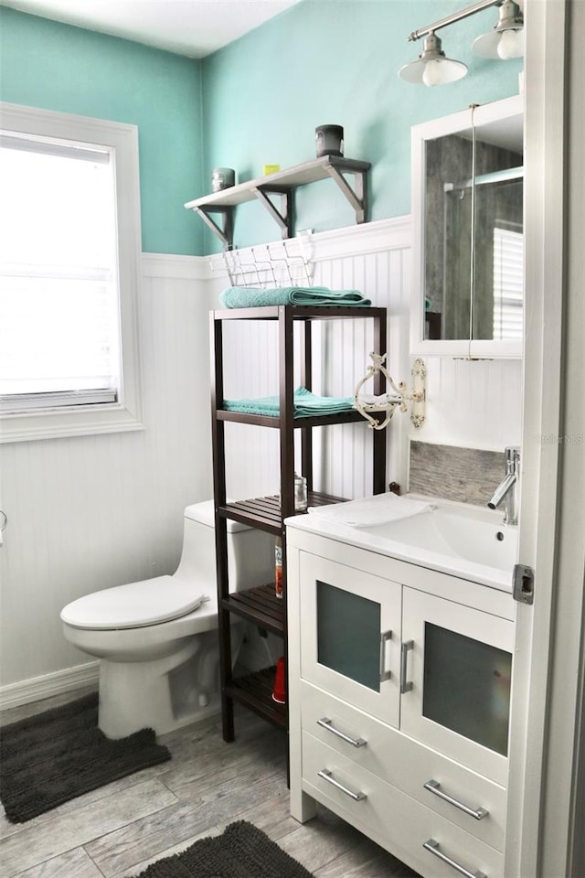 bathroom featuring wainscoting, vanity, toilet, and wood finished floors