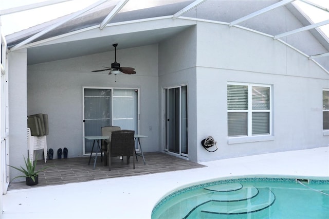 exterior space featuring glass enclosure, a patio area, and a ceiling fan