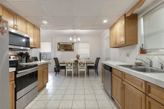 kitchen featuring tasteful backsplash, appliances with stainless steel finishes, light countertops, a sink, and light tile patterned flooring