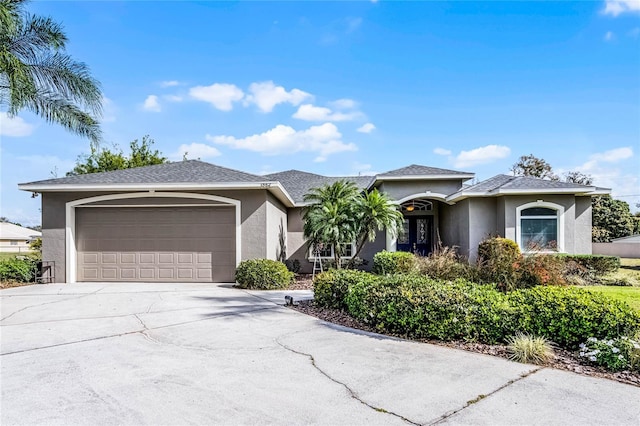 view of front of home with a garage, driveway, a shingled roof, and stucco siding