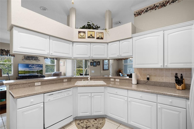 kitchen with light tile patterned floors, backsplash, white cabinetry, a sink, and dishwasher