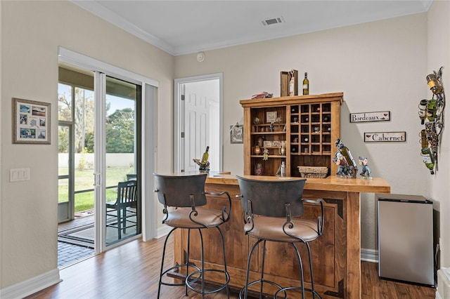 bar featuring ornamental molding, plenty of natural light, and wood finished floors