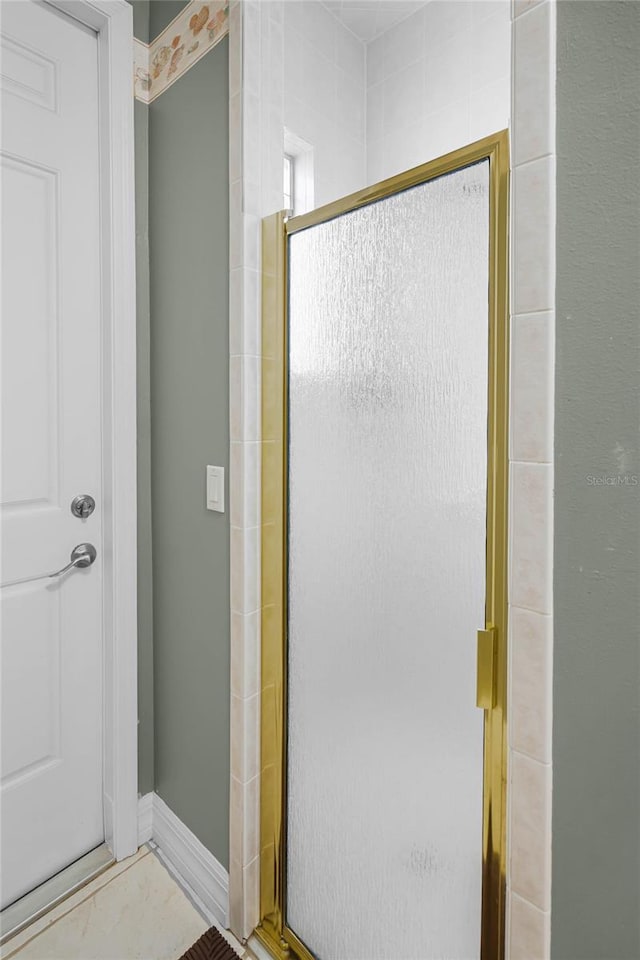 bathroom featuring a shower stall and baseboards