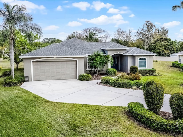 ranch-style home with roof with shingles, stucco siding, concrete driveway, an attached garage, and a front yard