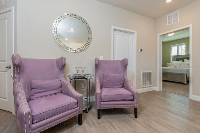 sitting room with visible vents, baseboards, and wood finished floors