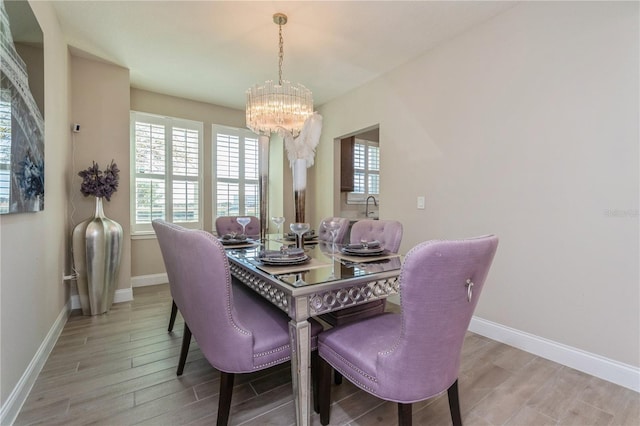 dining area featuring light wood-style floors, baseboards, and a chandelier