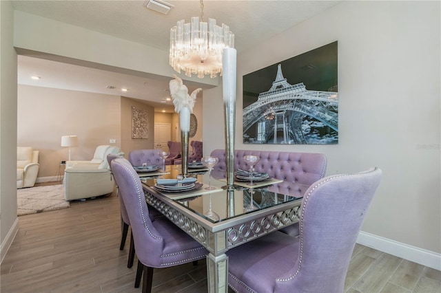 dining space with recessed lighting, visible vents, an inviting chandelier, wood finished floors, and baseboards