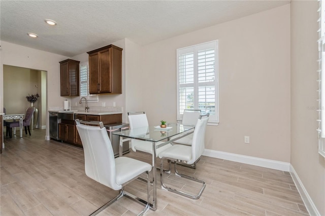 dining space with a textured ceiling, recessed lighting, light wood-style flooring, and baseboards