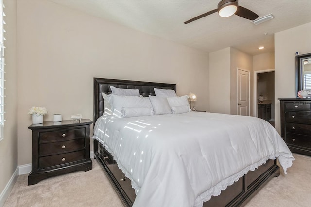 bedroom with light colored carpet, visible vents, connected bathroom, ceiling fan, and baseboards