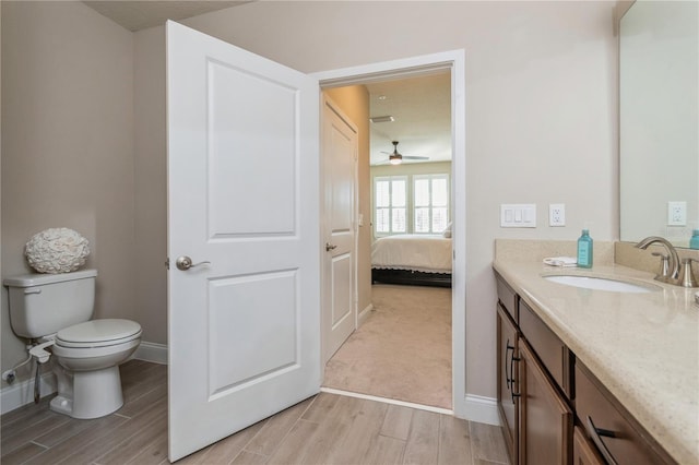 ensuite bathroom featuring toilet, ensuite bathroom, wood tiled floor, vanity, and baseboards