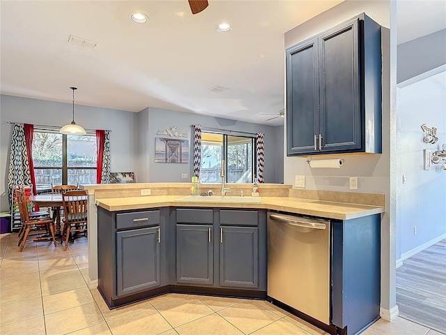 kitchen featuring light countertops, stainless steel dishwasher, a ceiling fan, a sink, and a peninsula