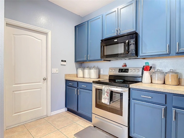 kitchen featuring black microwave, light tile patterned floors, blue cabinets, stainless steel range with electric cooktop, and light countertops