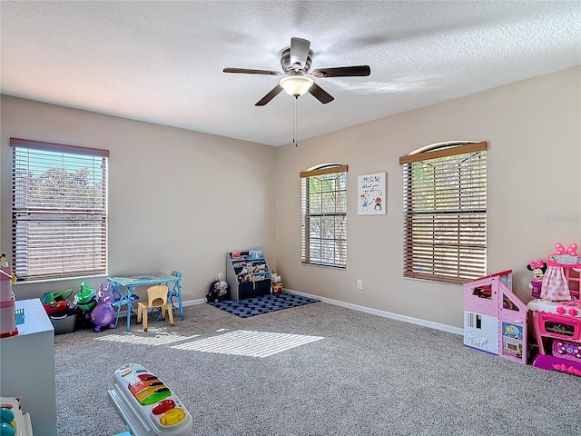 recreation room featuring carpet flooring, ceiling fan, a textured ceiling, and baseboards