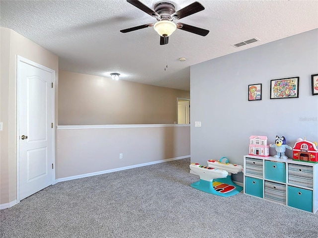 rec room featuring carpet, visible vents, ceiling fan, and a textured ceiling