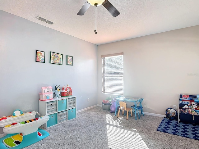 playroom with baseboards, visible vents, a ceiling fan, a textured ceiling, and carpet floors