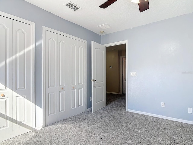 unfurnished bedroom with a textured ceiling, ceiling fan, carpet floors, visible vents, and baseboards