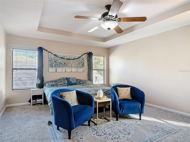 bedroom featuring a tray ceiling, carpet flooring, a textured ceiling, and baseboards