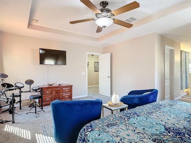 bedroom with a tray ceiling, carpet flooring, visible vents, and baseboards