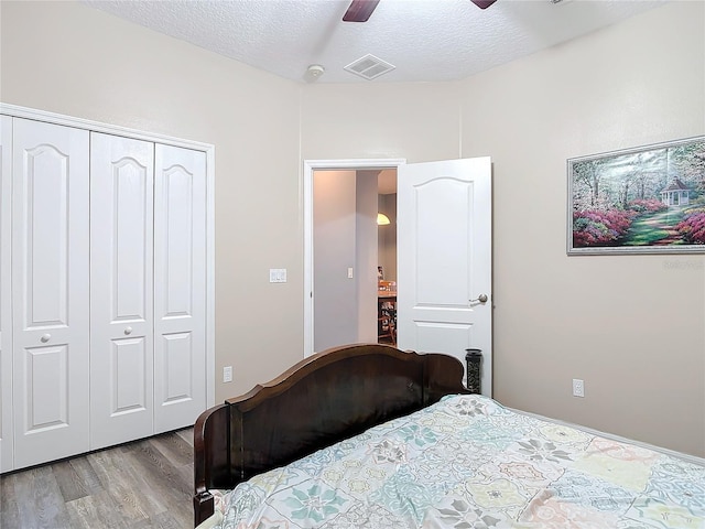 bedroom featuring visible vents, light wood-style flooring, ceiling fan, a textured ceiling, and a closet