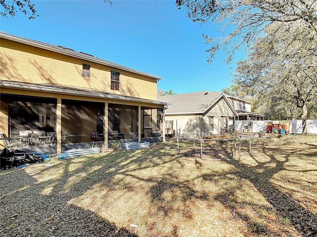 rear view of property with fence, a sunroom, and stucco siding