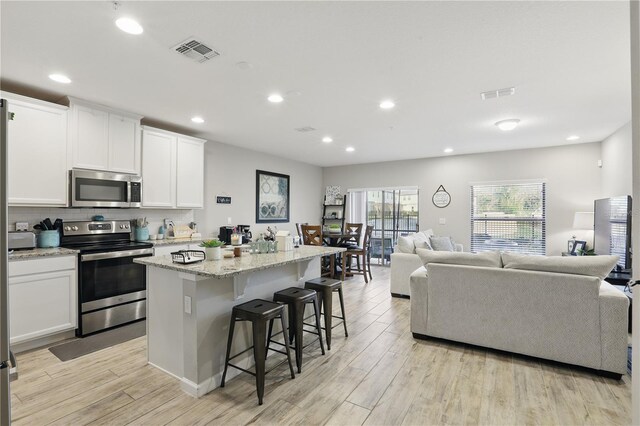 kitchen featuring open floor plan, stainless steel appliances, light wood-style flooring, and visible vents