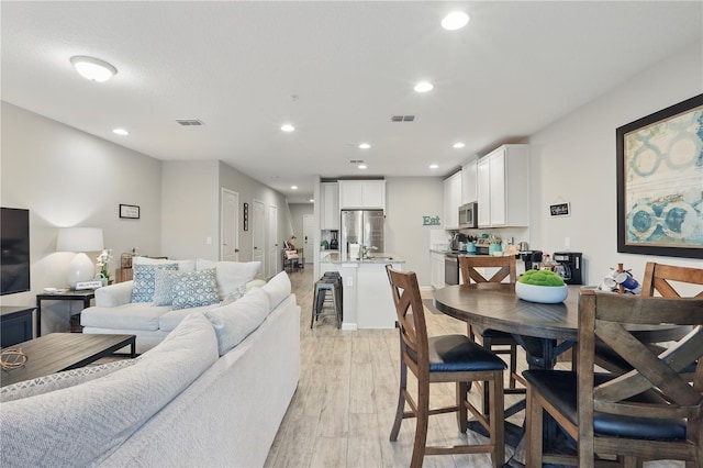 living area with light wood-type flooring, visible vents, and recessed lighting