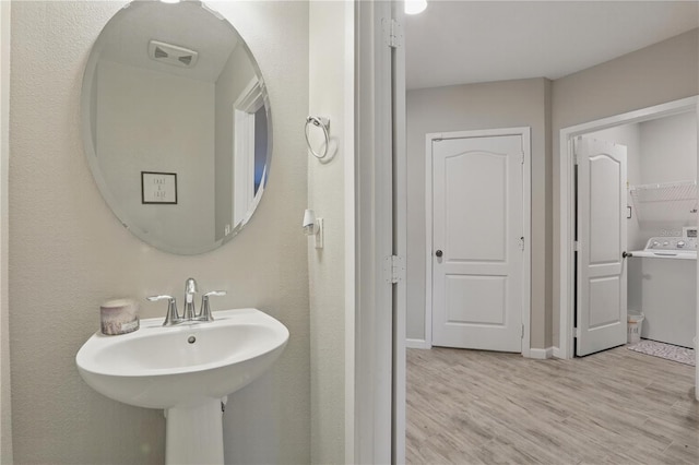 bathroom featuring a sink, wood finished floors, washer / dryer, and baseboards